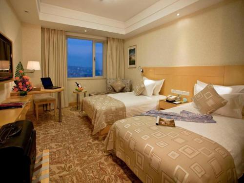a hotel room with two beds and a desk at Huachen Kenzo Hotel Hangzhou in Hangzhou