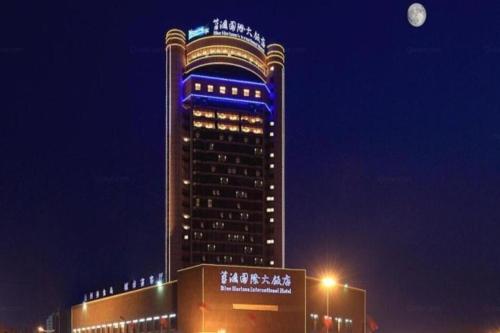 a tall building with a blue sign on it at night at Linyi Blue Horizon Intenational Hotel in Linyi