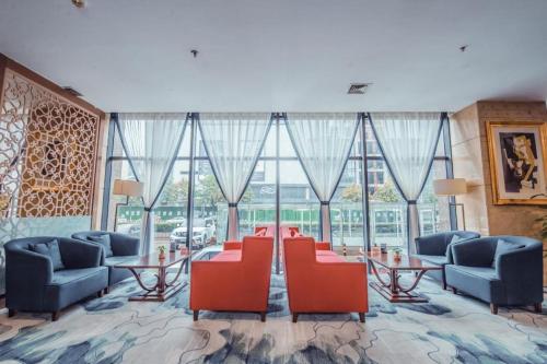 a lobby with red chairs and tables and windows at Linyi Blue Horizon Intenational Hotel in Linyi