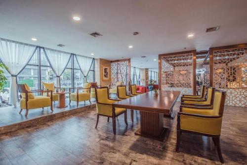 a dining room with a table and yellow chairs at Linyi Blue Horizon Intenational Hotel in Linyi