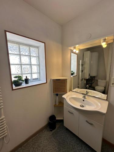 une salle de bain blanche avec un lavabo et une fenêtre dans l'établissement Maison au cœur de Villandry, à Villandry