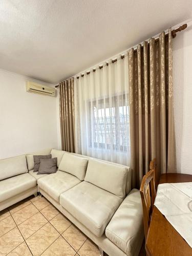 a living room with a white couch and a window at Lera Apartment Shkoder in Shkodër