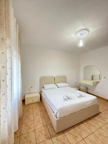a bedroom with a white bed and a mirror at Lera Apartment Shkoder in Shkodër