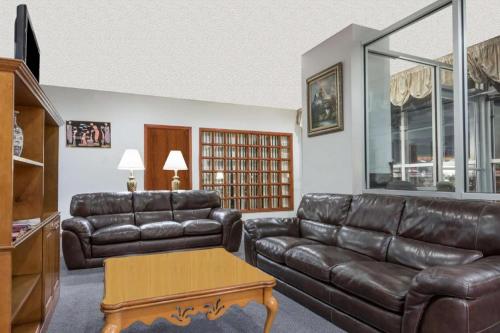 a living room with a leather couch and a table at Ramada Limited Norfolk in Norfolk