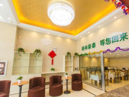 a restaurant with chairs and tables in a room at GreenTree Inn Taizhou New District Hospital of Renmin Hospital Mingliu Express Hotel in Jiuligou