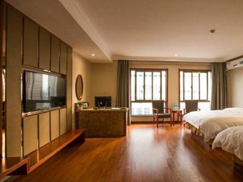 a bedroom with a bed and a flat screen tv at GreenTree Inn ChiZhou QinGYAng Miaoqian Road Rongxing Building Business Hotel in Chizhou