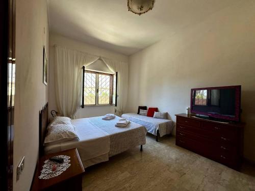 a bedroom with two beds and a flat screen tv at Casa via Appia Scauri - luminosa, grande a 250 m dal mare e dalla stazione ferroviaria in Scauri