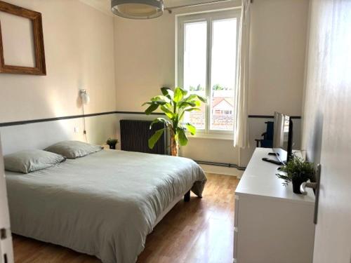 - une chambre avec un lit et un bureau avec une plante dans l'établissement GRAND APPARTEMENT DE CARACTERE à VICHY, à Vichy