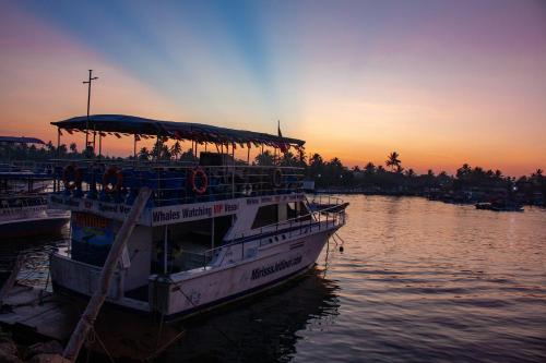 a boat is docked in the water at sunset at Parangi Weligama Bay - Thema Collection in Weligama