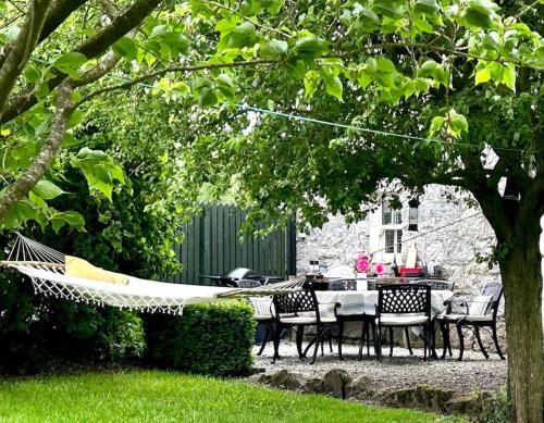 a hammock in a garden with a table and chairs at The Gables Cottage in Rathvilly