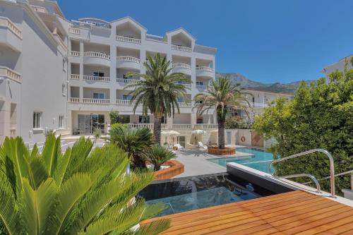 a hotel with a swimming pool and palm trees at Hotel Laurentum in Tučepi
