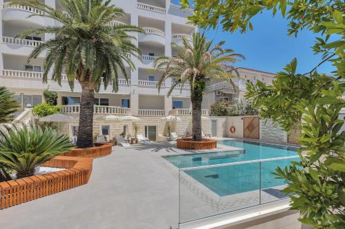 an image of a hotel with a swimming pool and palm trees at Hotel Laurentum in Tučepi