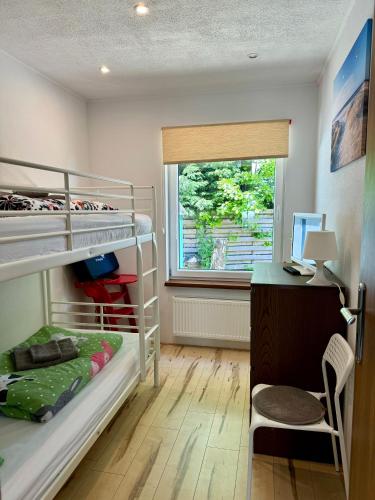 a bedroom with bunk beds and a desk and a window at Villa Blue Sky in Heinkensand