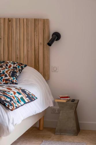 a bedroom with a bed with a wooden headboard and a lamp at Clos Marcamps - Teritoria in Prignac-et-Marcamps