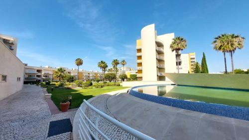 a swimming pool in front of a building with palm trees at Vilamoura TOP MouraPraia in Vilamoura