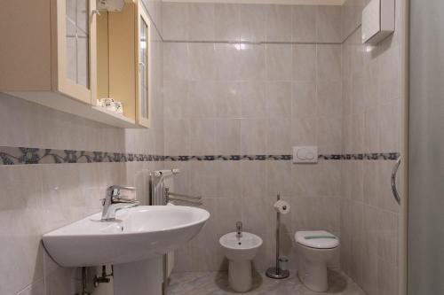 a white bathroom with a sink and a toilet at Hotel Oberdan Ristorante Pizzeria in Concordia Sagittaria