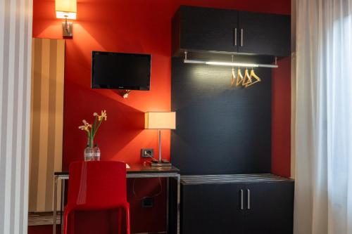 a room with a red wall with a desk and a tv at Hotel Oberdan Ristorante Pizzeria in Concordia Sagittaria
