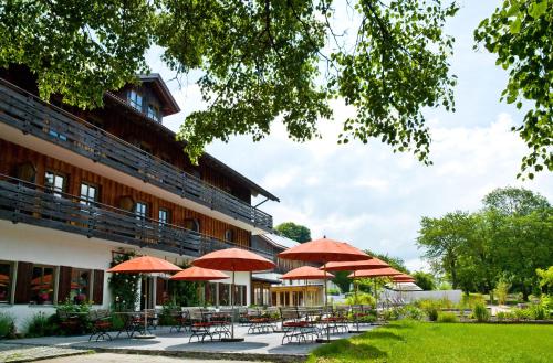 un hotel con tavoli, sedie e ombrelloni di Biohotel Pausnhof a Sankt Oswald