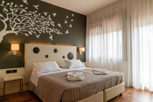 a bedroom with a bed with a tree on the wall at Hotel Oberdan Ristorante Pizzeria in Concordia Sagittaria
