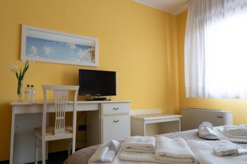 a bedroom with a bed and a desk with a television at Hotel Oberdan Ristorante Pizzeria in Concordia Sagittaria