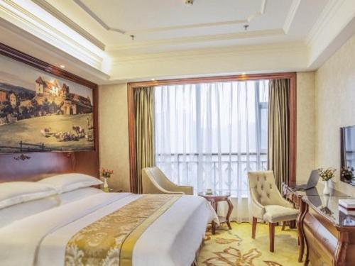 a bedroom with a large bed and a desk and a window at Vienna Hotel Guiyang Jiaxiulou Jichang Road in Guiyang