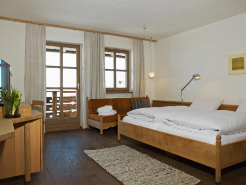 a bedroom with a bed and a couch and windows at Biohotel Pausnhof in Sankt Oswald
