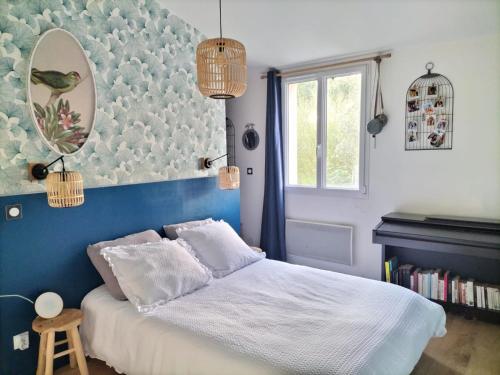 une chambre avec un lit avec un mur bleu dans l'établissement Maison Familiale à la campagne, à Saint-ouen-dʼAunis