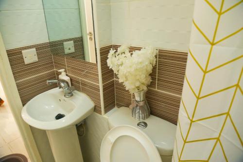 a bathroom with a sink and a toilet and a vase of flowers at 1 bedroom Greenzone Apartment Thindigua, Kiambu Road in Nairobi