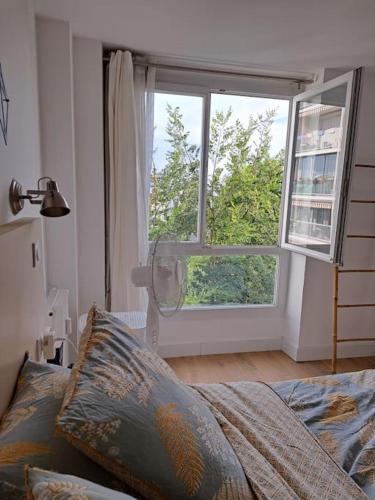 une chambre avec un lit et une grande fenêtre dans l'établissement Grand appartement lumineux Rennes, à Rennes