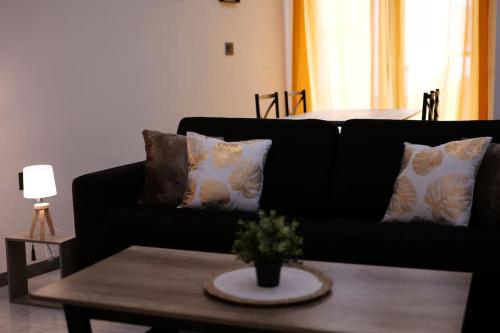 a living room with a black couch and a table at Le Cocon Capestanais in Capestang