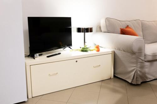 a living room with a tv and a white couch at Ca' Spadoni, centro storico, piano terra, ingresso indipendente, teatro, parcheggio, in Imola