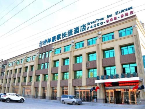 a building with cars parked in front of it at GreenTree Inn Liaocheng Donge Culture Street Express Hotel in Liaocheng