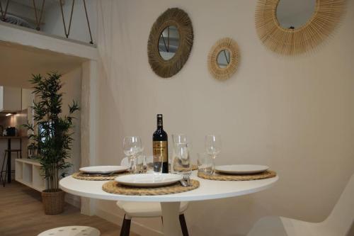 une table blanche avec des verres, des bouteilles de vin et des miroirs dans l'établissement Le bambou - Appartement avec terrasse, à Marseille