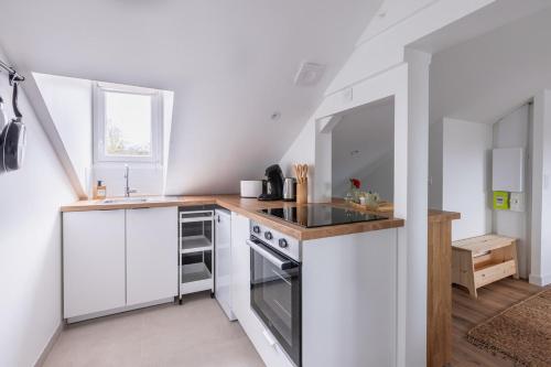 une cuisine avec des armoires blanches et un four à plaques de cuisson dans l'établissement Le Bourbonnais ~ Mansardé ~ Arrivée Autonome, à Montluçon