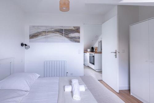 une chambre blanche avec un lit et une cuisine dans l'établissement Le Bourbonnais ~ Mansardé ~ Arrivée Autonome, à Montluçon