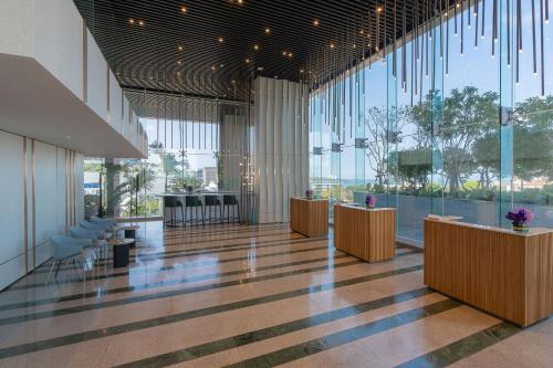 a lobby with tables and chairs and large windows at Akara Hotel Pattaya in Pattaya North