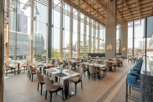 a restaurant with tables and chairs and large windows at Akara Hotel Pattaya in Pattaya North
