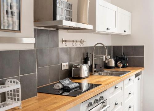 une cuisine avec des armoires blanches et un évier dans l'établissement OIQIA • Épicure, à Colmar