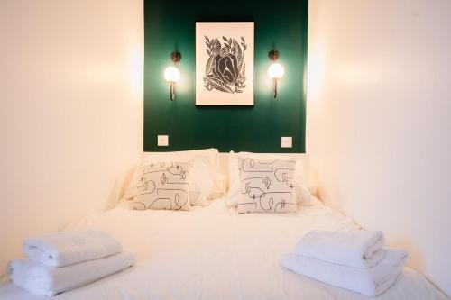 - un lit blanc avec deux oreillers et un mur vert dans l'établissement OIQIA • Jadéa • Émeraude, à Bressuire