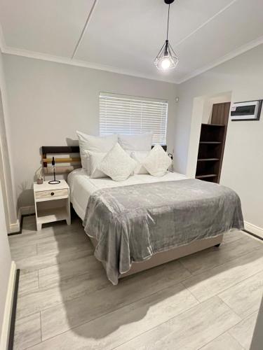 a white bedroom with a large bed and a table at Familia in Pietermaritzburg
