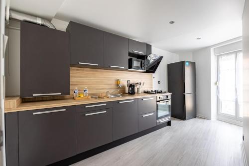 une cuisine avec des armoires noires et des appareils en acier inoxydable dans l'établissement OIQIA • Téralis • Mousson, à Annonay