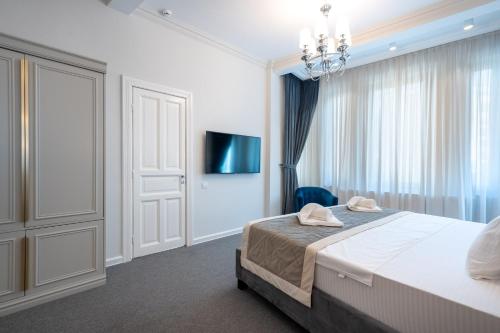 a white bedroom with a bed and a chandelier at HIGHLINE DOWNTOWN ApartHotel OLDTOWN UNIRII SQUARE in Bucharest