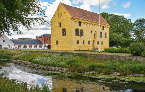 an old yellow building next to a river at 1 Bedroom Nice Home In Tomelilla in Tomelilla