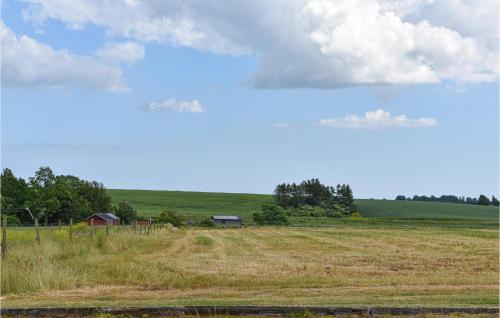 a field with a farm in the distance with a sky at 1 Bedroom Nice Home In Tomelilla in Tomelilla