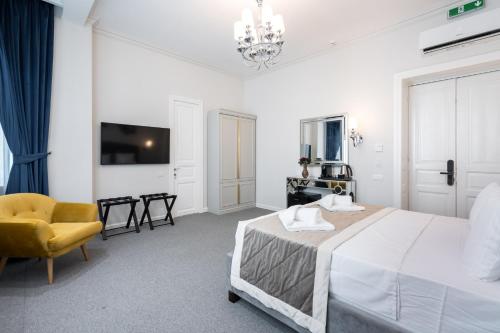 a white bedroom with a bed and a chair at HIGHLINE DOWNTOWN ApartHotel OLDTOWN UNIRII SQUARE in Bucharest