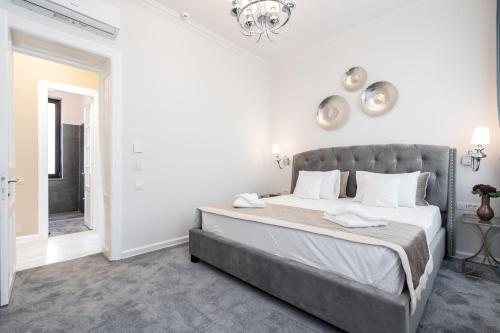 a white bedroom with a large bed and a chandelier at HIGHLINE DOWNTOWN ApartHotel OLDTOWN UNIRII SQUARE in Bucharest