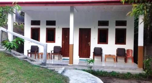 a group of chairs sitting outside of a house at Tangkoko Macaca in Rinondoran