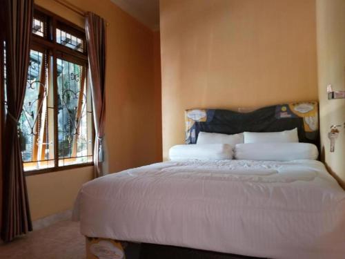 a bedroom with a large white bed with a window at Algira Homestay Prambanan in Prambanan