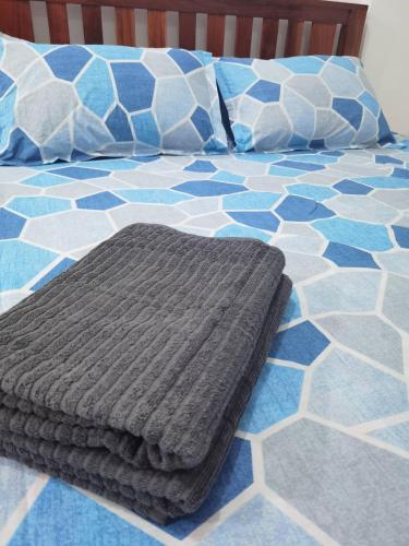 a bed with a grey blanket and pillows on it at Casa Kristar in Mamburao