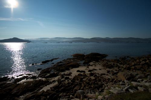 a group of rocks on the shore of a body of water at A Maquia in Poio